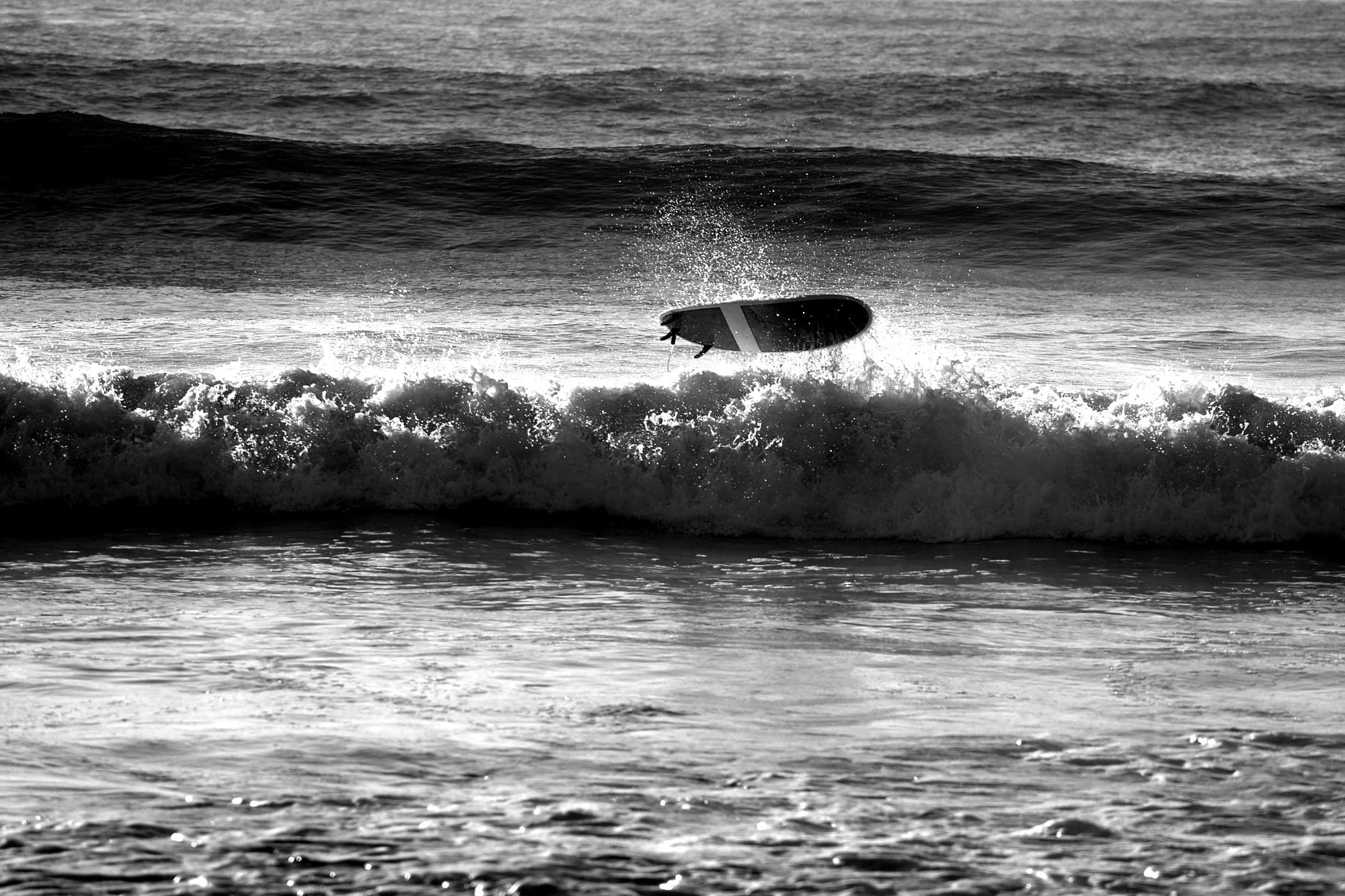 A surfboard thrown up by a breaking wave off a Southern Maine beach